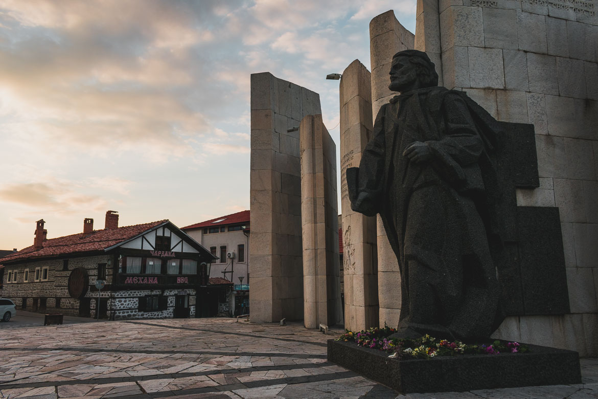 This photo shows Paisii Hilendarski monument in Bansko main square. Hoppa airport transfers. How to get from Sofia to Bansko Bulgaria.