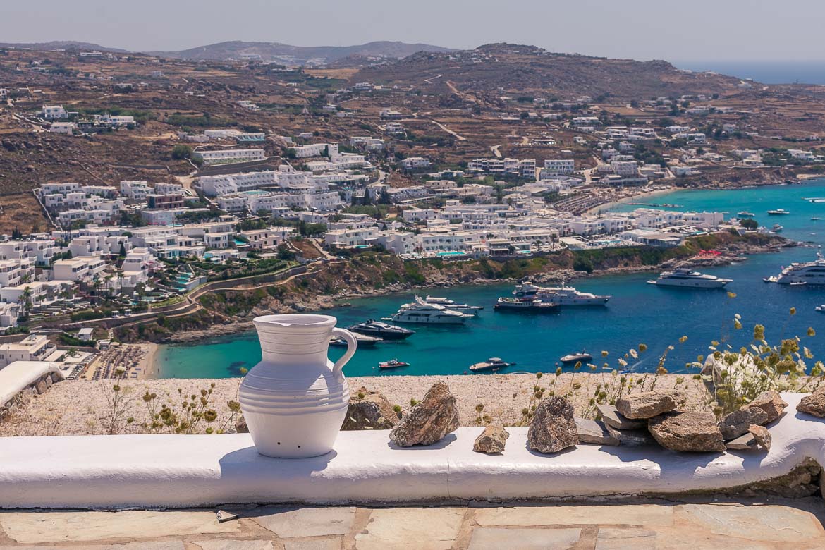 This is a view of Psarou Beach in Mykonos. The hill above the beach is excessively overbuilt with luxury villas while the sea is abundant in yachts.