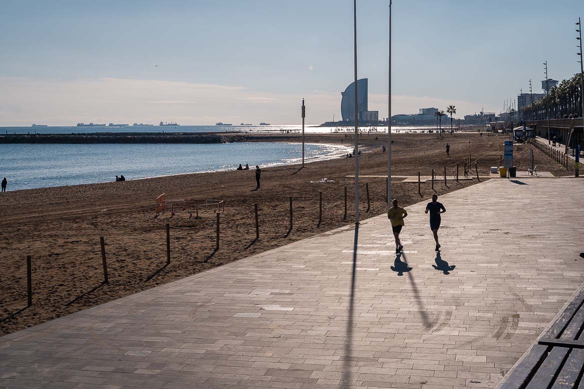 Two men running along La Barceloneta beach.