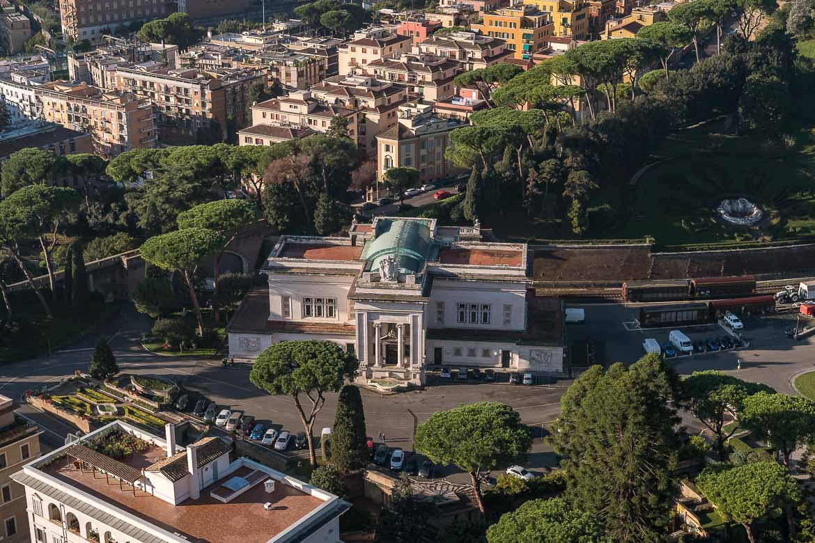 This is a panoramic shot of the Vatican City from the top of the Dome of St. Peter's Basilica. Central to the photo is the building of the Vatican Railway Station.