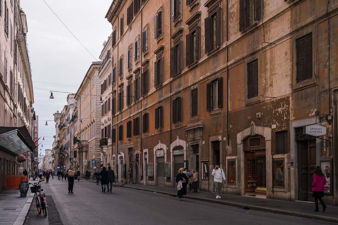 This image shows a section of Via del Corso. There are many people walking, shopping and chatting.