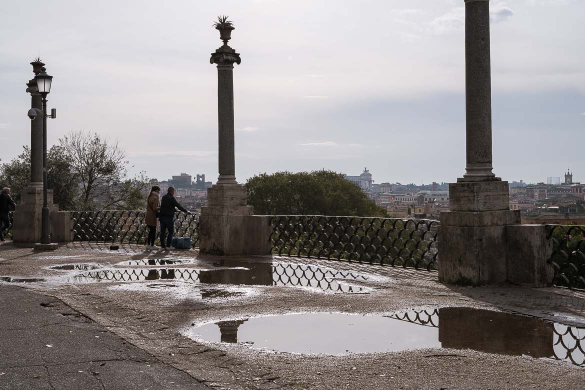This image shows Terrazza Viale del Belvedere after the rain. There are puddles of water reflecting the view of Rome beyond.