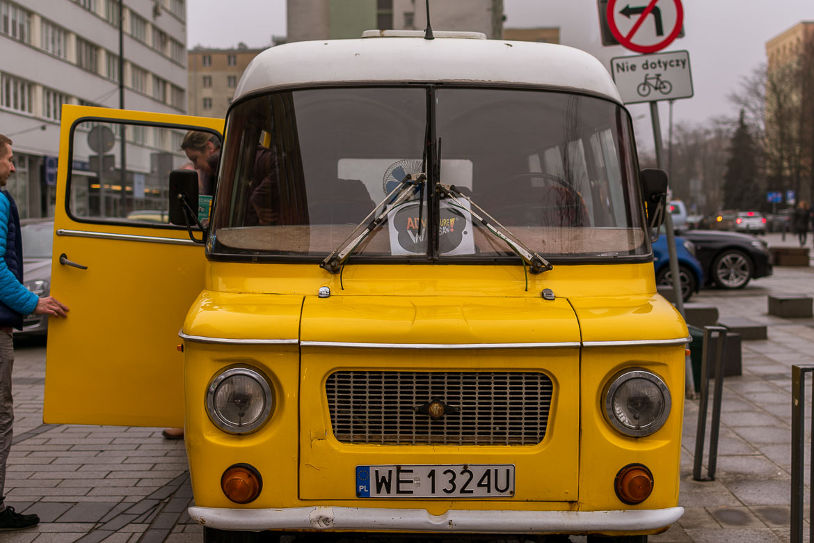 This is the front part of a yellow vintage Nysa van. Maria is getting off from the back door.