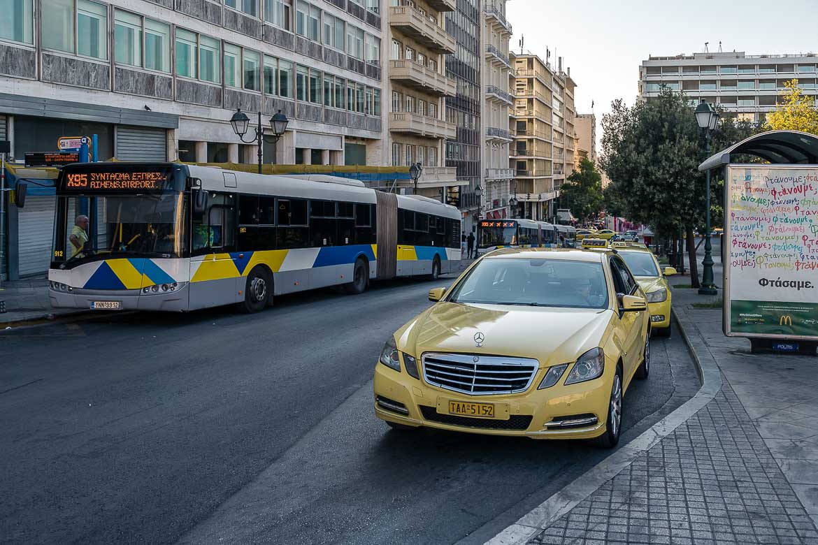 This image shows the X95 bus, which goes to Athens airport, and a line of taxis at Syntagma square.