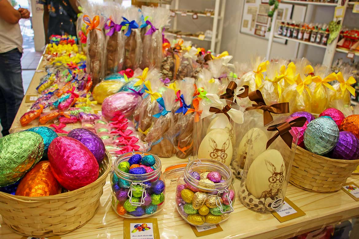 This is a close up of a table full of Easter treats for sale. There are chocolate eggs of all sizes covered in colourful paper. There are also chocolate bunnies and other animals.