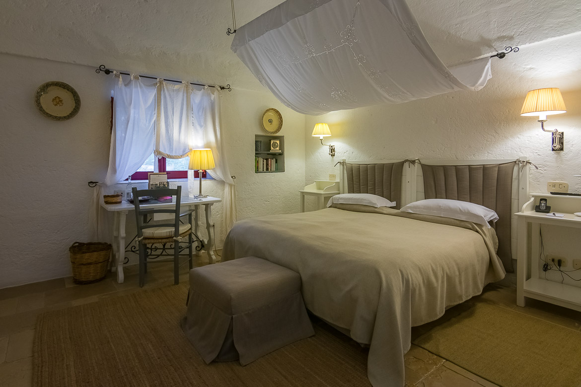 This image shows our room at Masseria Torre Coccaro. It is decorated in white and light grey. It is romantic, luxurious yet cosy with a traditional touch. 