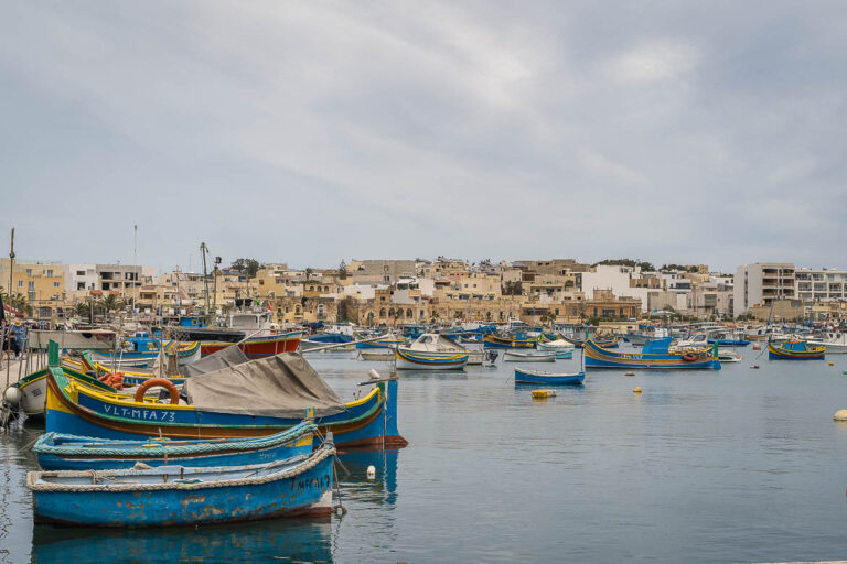 Panoramic view of Marsaxlokk harbour where numerous blue traditional boats are mooring.