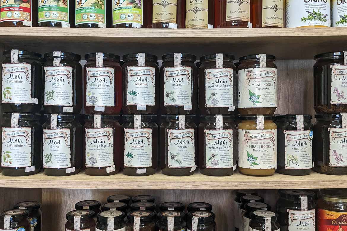 Several vases with different kinds of honey on a grocery's shelf.