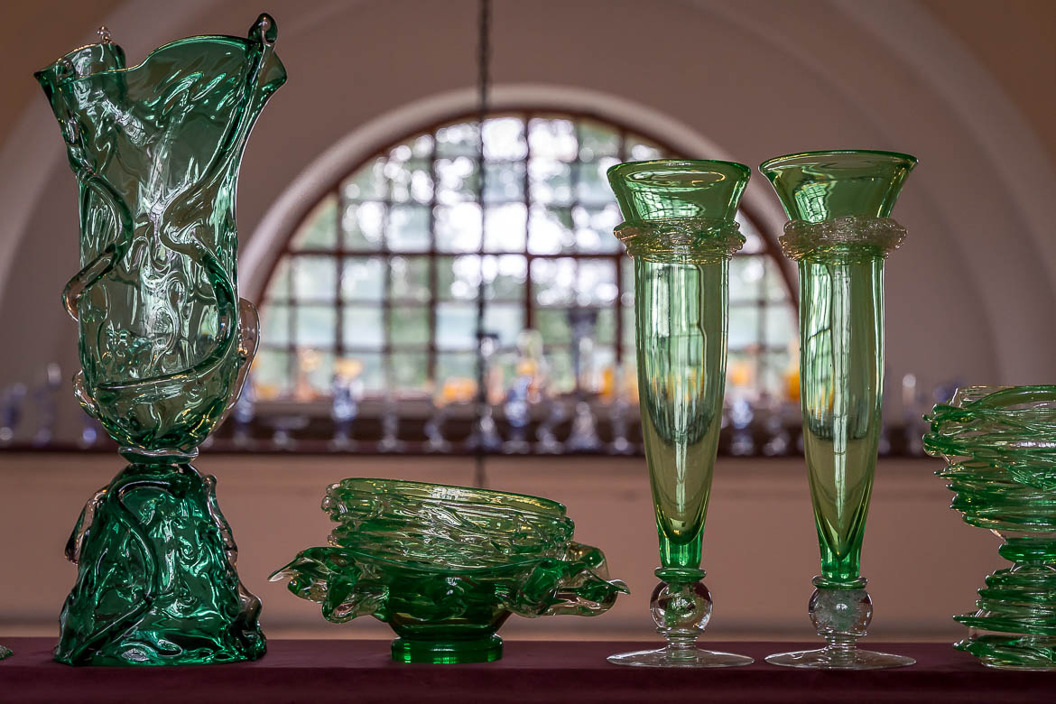 This photo shows elaborate green vases made of Bohemia crystal standing on a short wall of a church.