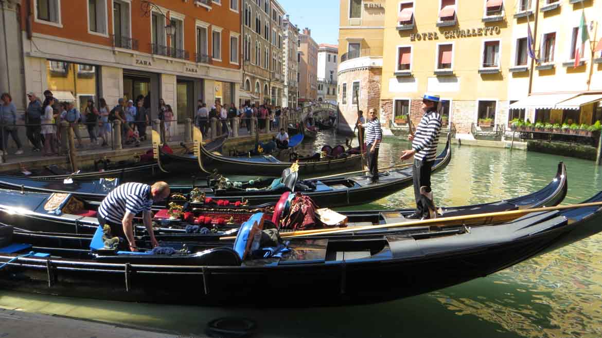This picture shows gondolas waiting in line to take visitors for a private gondola ride on the canals of Venice, Italy. Top things to do in Venice. What to do in Venice.