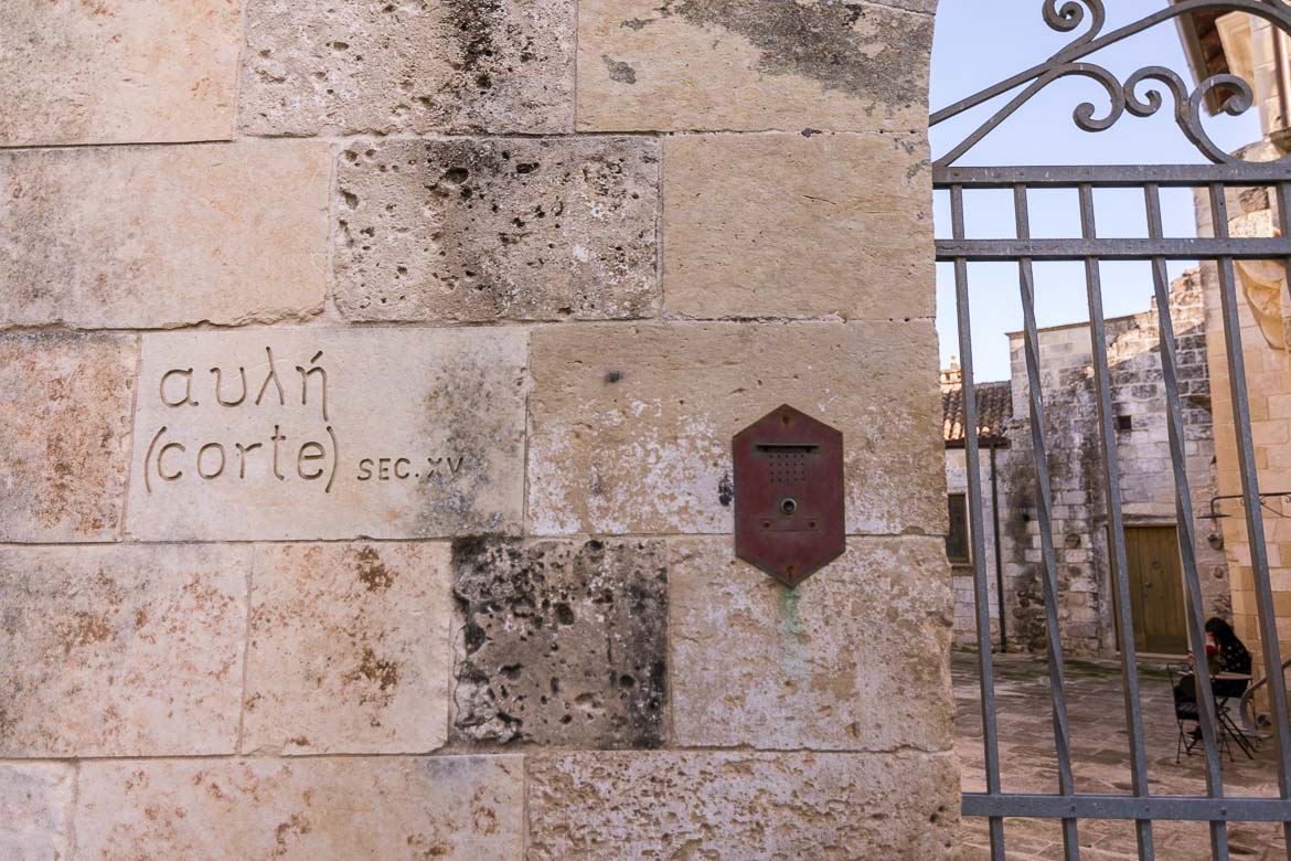 This is a close up of a wall sign that reads αυλή and corte. 