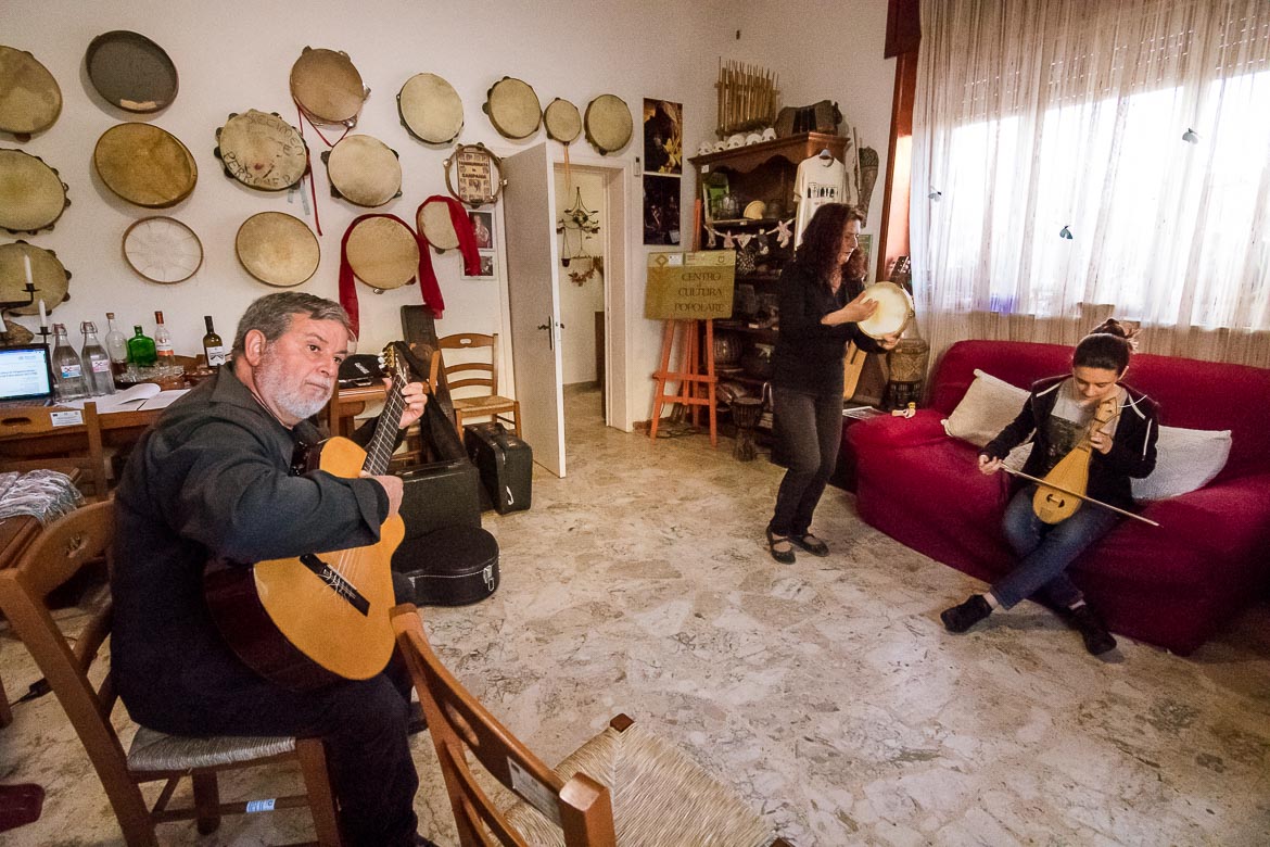 This picture shows Salvatore playing the guitar, Mariella playing the tambourine and singing and Letizia playing the lyre inside Melpignano Cultural Centre. 
