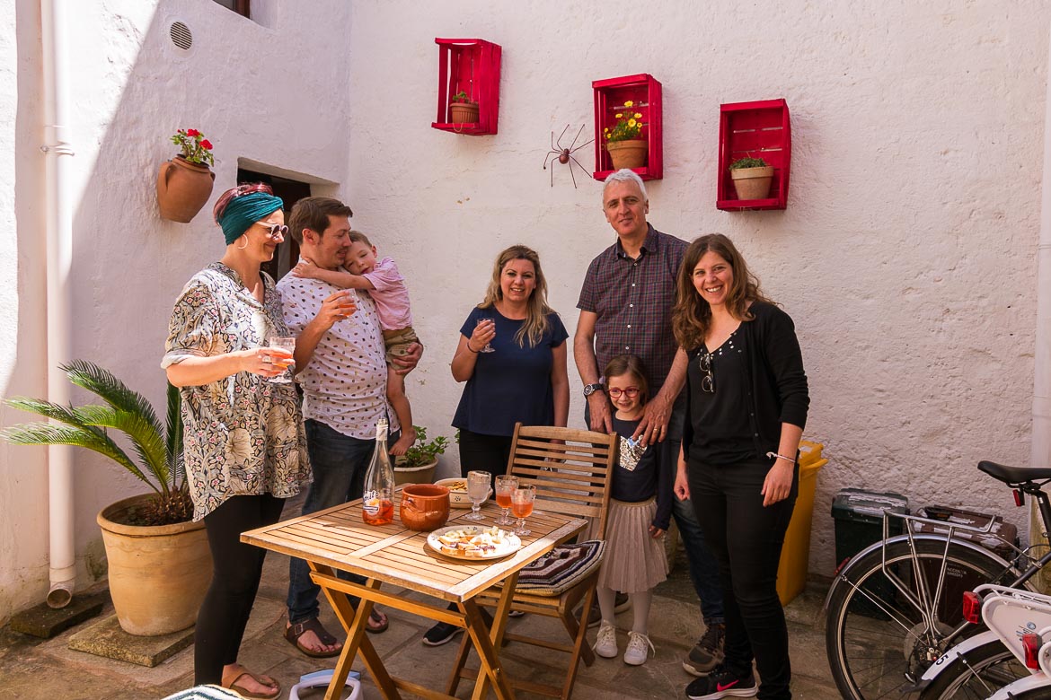 This photo shows Maria, Katerina and a party of 4 more people raising their aperitivo glasses to toast. The setting is the courtyard of Corte Candelora B&B. One of the moments we cherish about our Grecia Salentina trip.