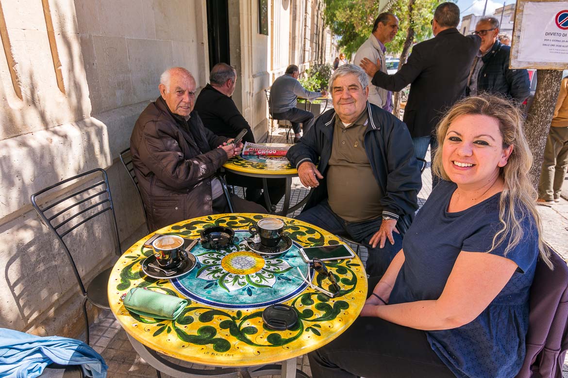This photo shows Maria sitting at an outside cafe with Mimmo and Uccio on a sunny day. 