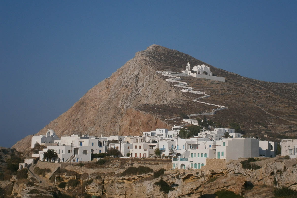Panoramic view of Folegandros Chora perched on the cliff with the imposing Panagia church above the hill.