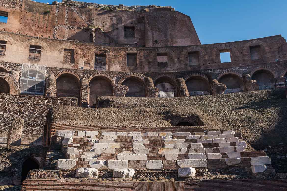 The seating area of the Colosseum. There are some marble seats with engravings on them.