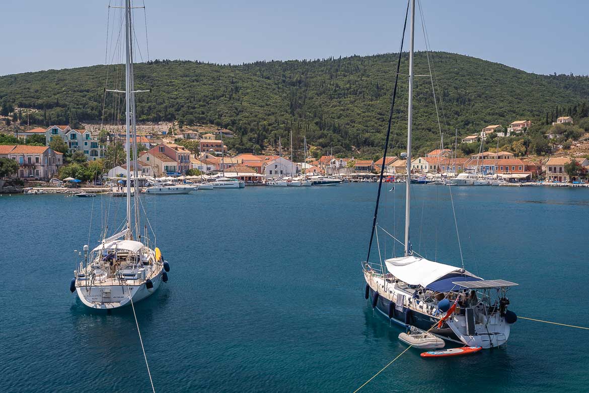 Panoramic view of two yachts moored in Fiskardo bay with the village in the background.