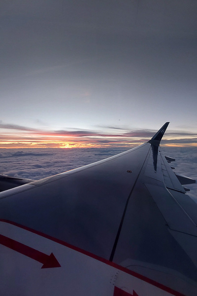 This image shows a sunset view over the clouds as seen from an airplane.