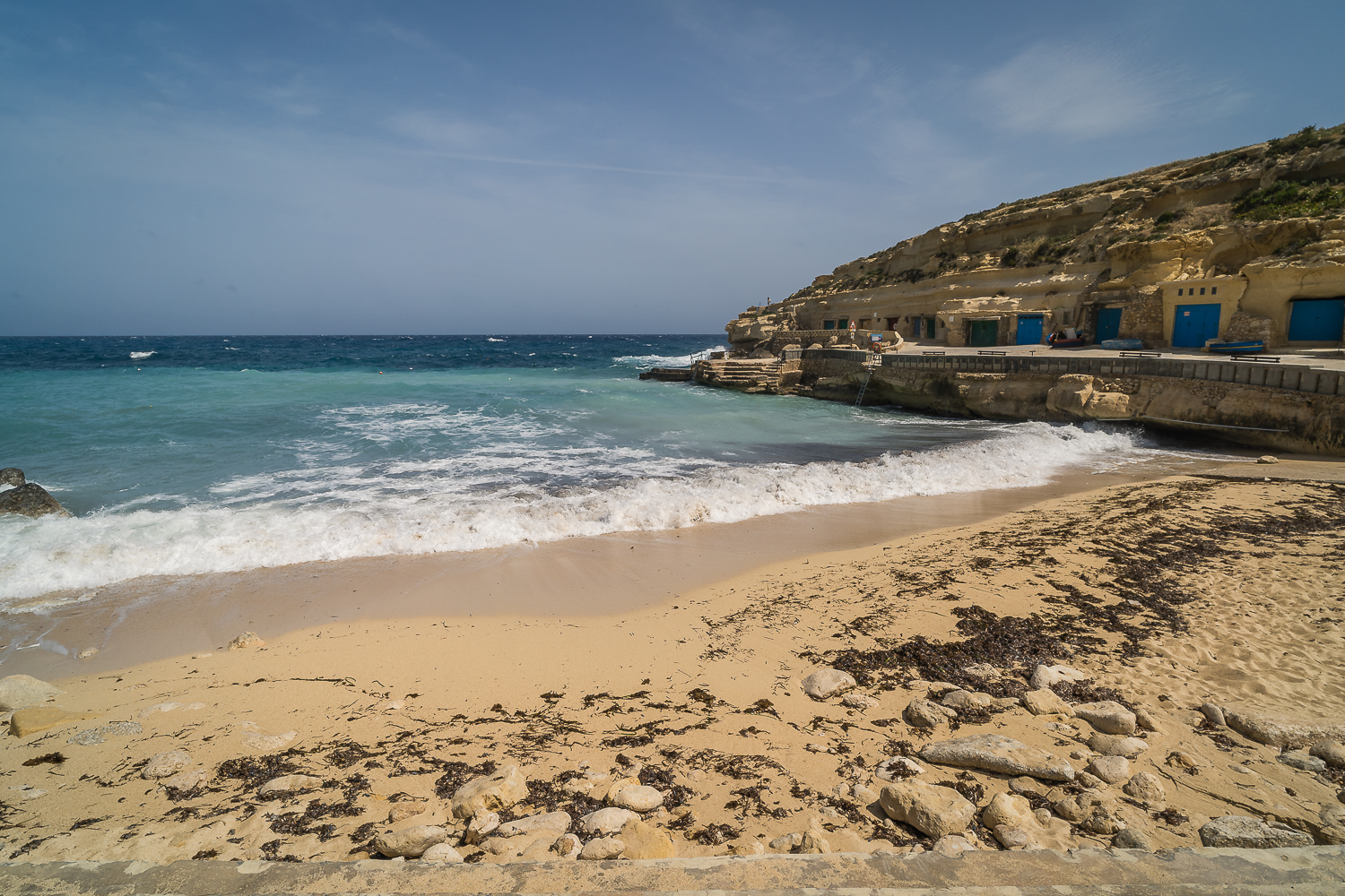 Rough sea at Hondoq ir-Rummien Bay. The sandy beach with turquoise waters is home to several fishermen sheds with colourful doors.