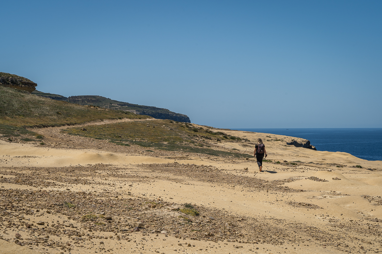 Maria is walking on a trail without shade in Gozo.