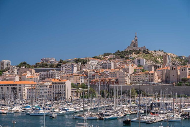 This image shows a panoramic view of the Old Port and La Notre-Dame de la Garde, one of the be.