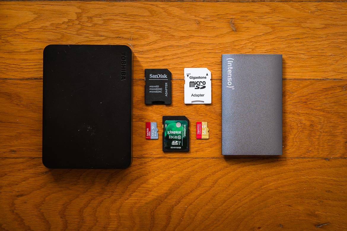 This image is a close up of two portable hard drives and five SD cards, all necessary items on your minimalist travel photography gear list. 