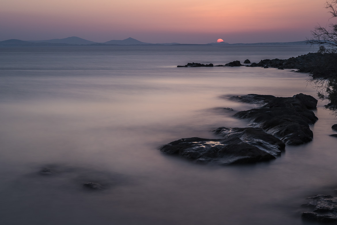 This is a long exposure shot during sunset that creates a smooth effect on the sea water. It was shot in Naxos Greece.