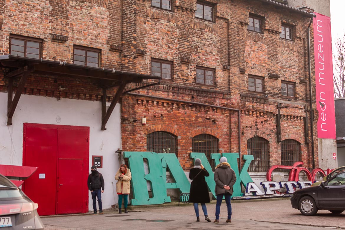 Outside the Neon Museum in Warsaw, there are neon signs and parked cars.