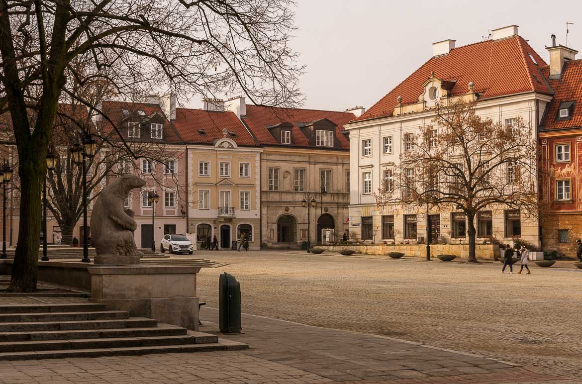 This image shows the New Town Market Square. It's lined with beautiful buildings with red-tiled roofs. On the left, there's a statue of a bear.