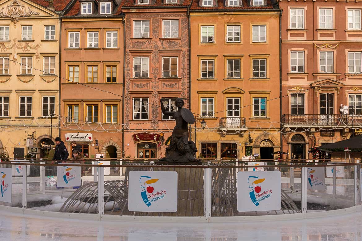 This image shows the Mermaid of Warsaw statue surrounded by an ice skating rink.