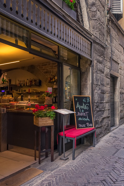 This image shows the entrance to Caffe Corsarola. There is a chalk board outside that reads: Aperitivo & Buffet €9 dalle 18:00.