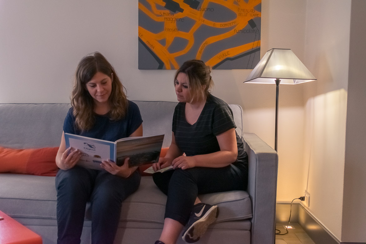 This image shows Maria and Katerina relaxing on the sofa at their room in Gombithotel. They are going over the pages of a book about the city.