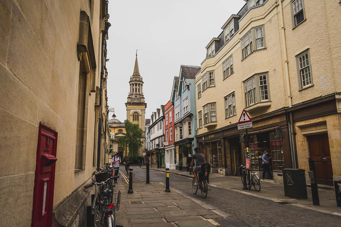 This photo shows a quaint cobblestone street in the centre of Oxford along which a lot of people walk or cycle.