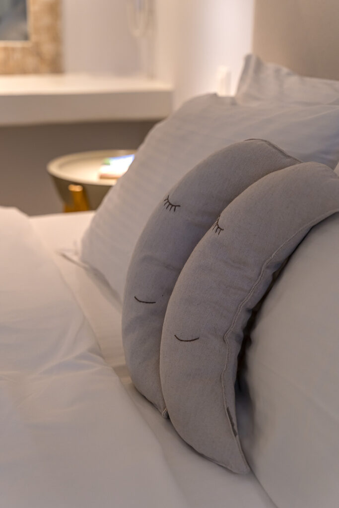This image shows the bed pillows in a room of Adonis Hotel in Paros.