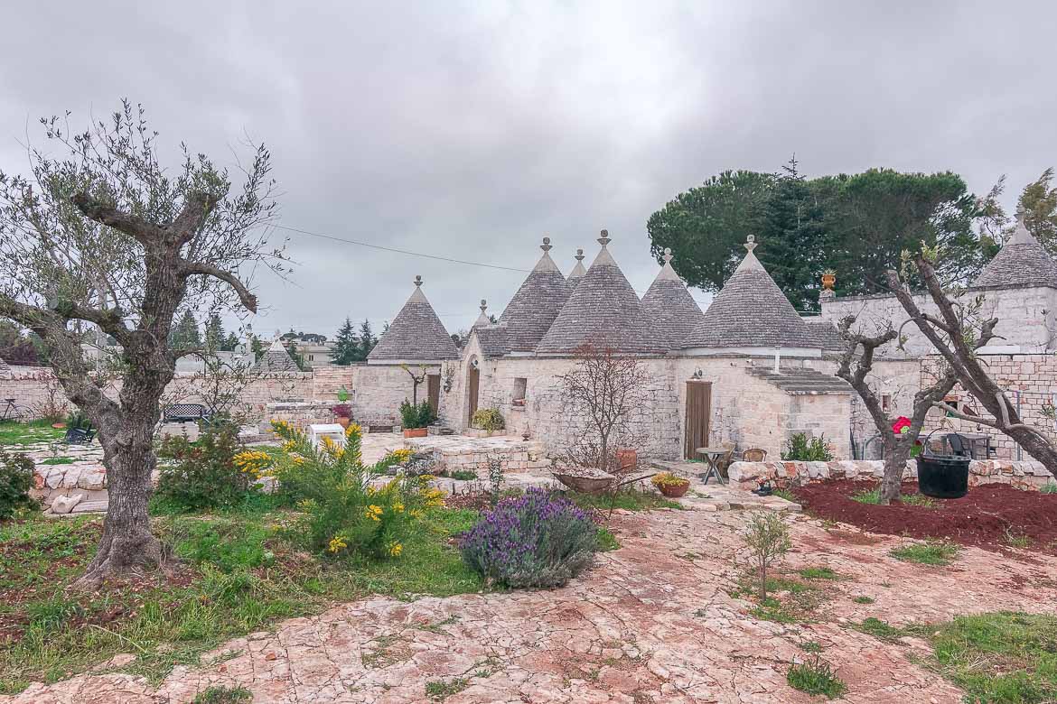 This image shows a complex of trulli, which are white round stone buildings with grey conical roofs. Puglia is abundant in trulli. You shouldn't miss the chance to stay at one during your Puglia road trip. This is Annalocos Trulli in Locorotondo. We spent one night there and loved it.