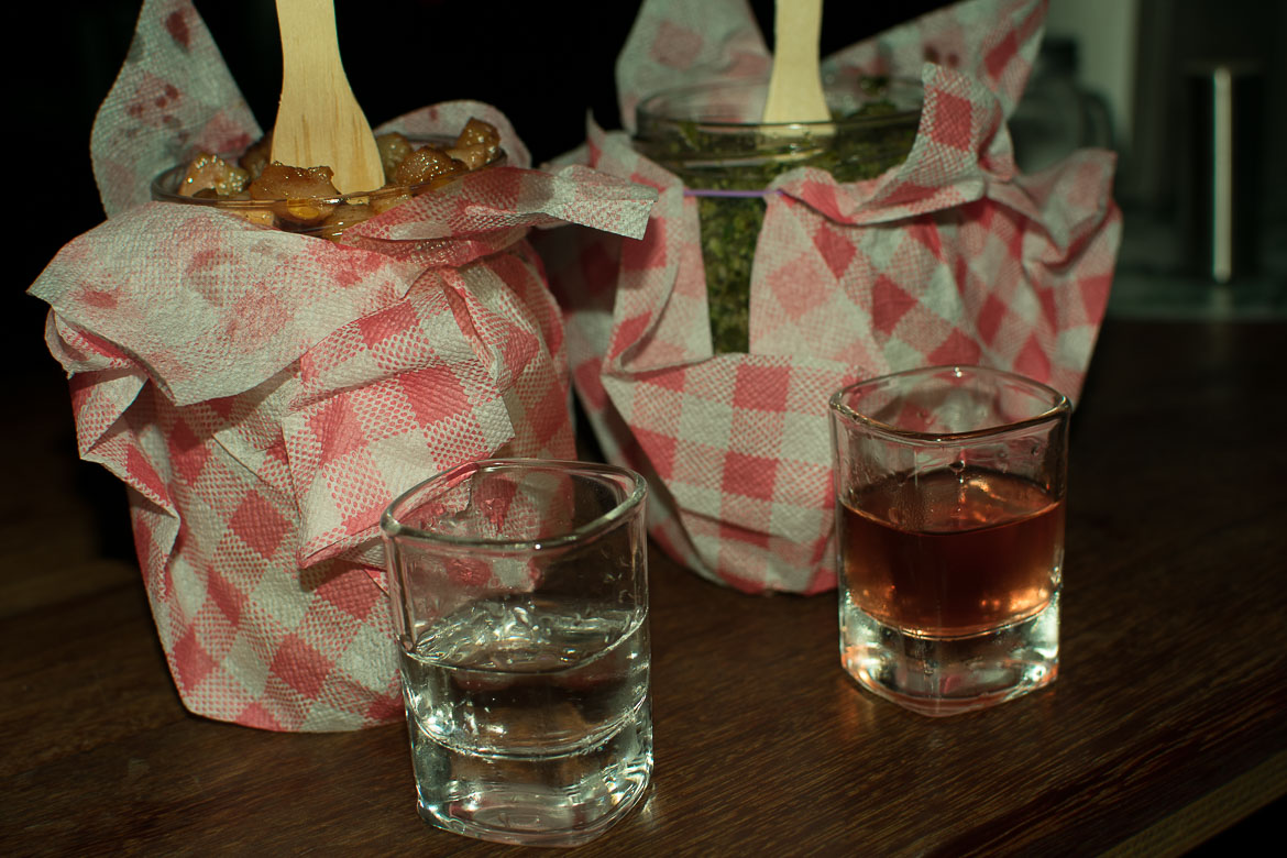 This image is a close-up of two jars filled with pyzy and two shots of homemade spirits.