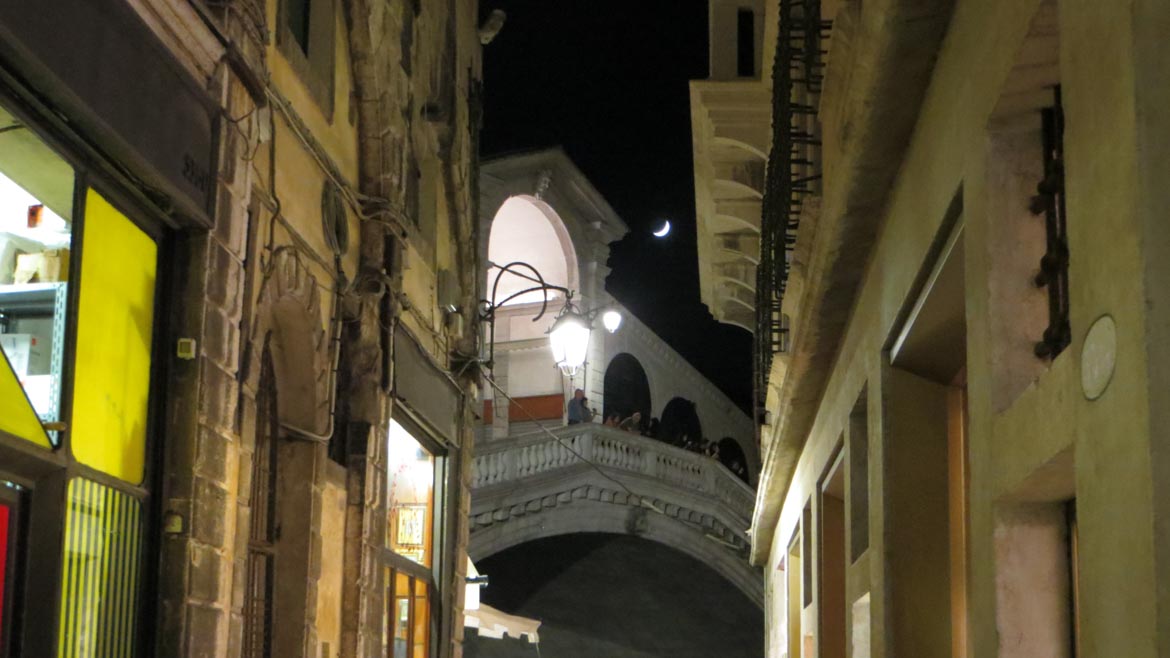 This is a photo of the Rialto bridge in Venice at night with the moon right above it. What to do in Venice: our complete guide to La Serenissima. Venice Italy.