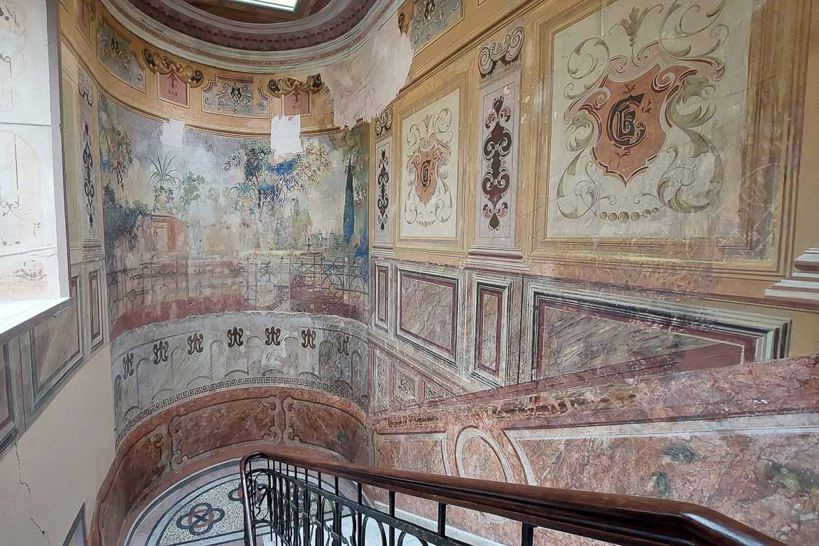 A grand staircase with elaborate hand-painted frescoes.