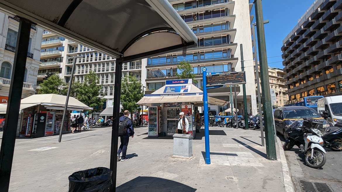 A bus stop on Syntagma Square. There is a digital board displaying bus arrivals.