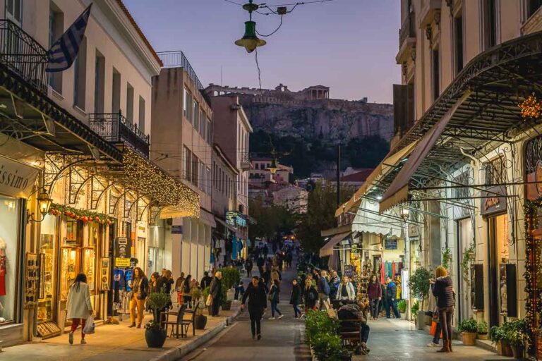 Aiolou street decorated at Christmas with the Acropolis in the background before dark.