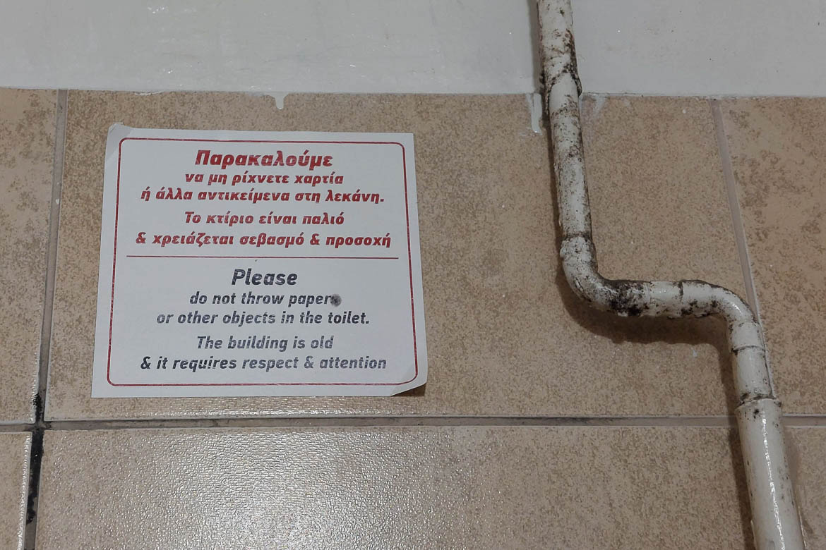A sign in a toilet that reads in Greek and in English: "Please do not throw paper or other objects in the toilet. The building is old and it requires respect and attention." This is one of the best travel tips for Athens to remember. 