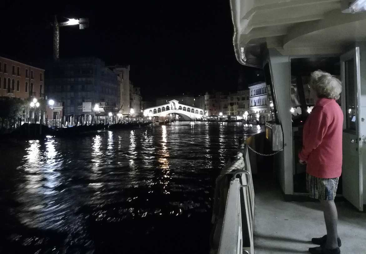 This photo shows the Rialto bridge in Venice as seen from a vaporetto at night. What to do in Venice: our complete guide to La Serenissima. Venice Italy.
