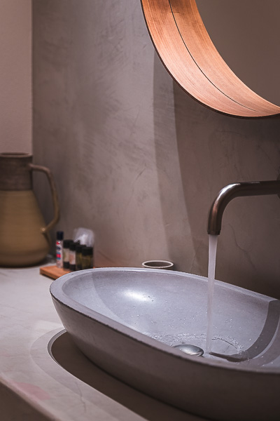 This is a close up of a tap with running water and a stone wash basin. 