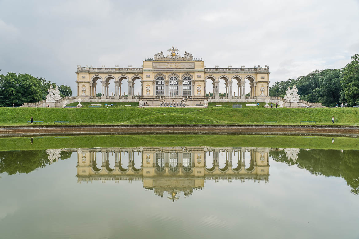 View of the Gloriette and its reflection on the pond in the foreground.