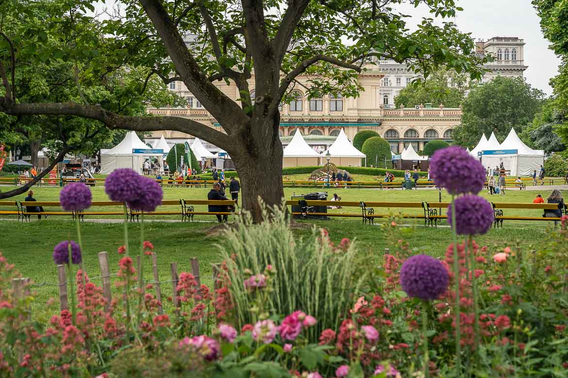 The park with several tents and benches in front of the Kursalon building in Stadtpark.