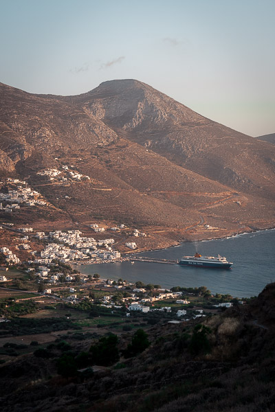 This is a panoramic shot of Aegiali Port as seen from Tholaria Village. There's a ferry that just left the port behind.