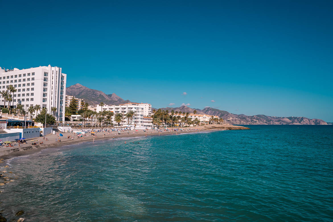 This image shows a beach lined with tall buildings. If you're wondering what to do in Nerja, hitting the beach should be at the top of your list. 