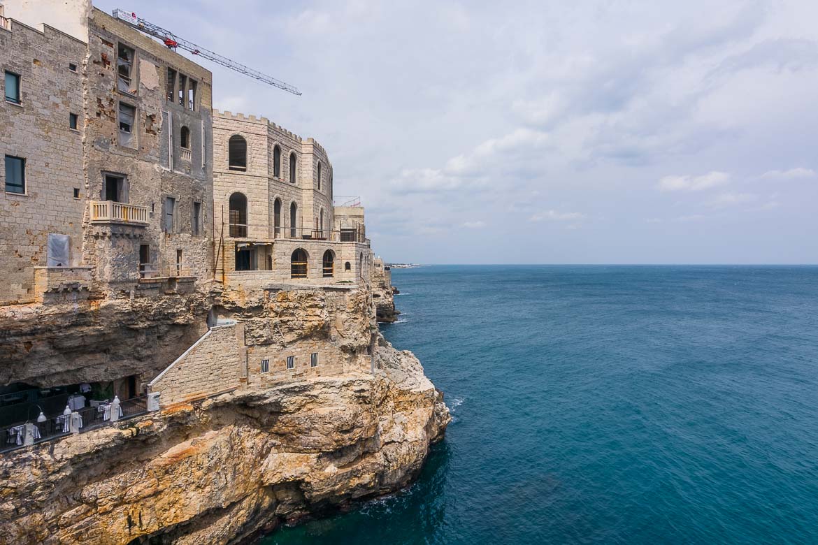 This photo shows a row of tables set inside a cave. This is Grotta Palazzese the most high-end restaurant in Polignano a Mare.