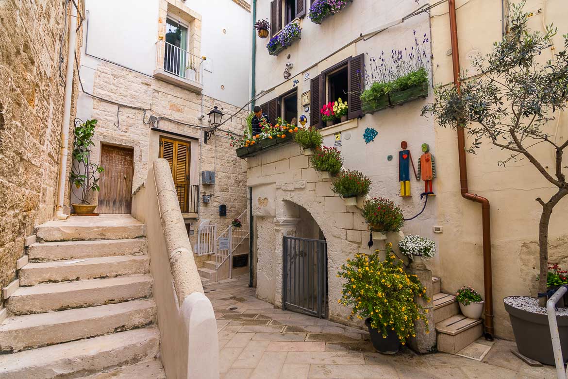 This is a photo of the Vicolo della Poesia in the Old town. It is a charming courtyard-like space filled with plants and flowers.
