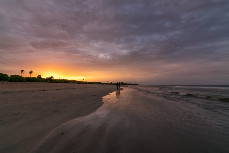 This photo shows Nilaveli Beach at sunset. There are two people walking on the sand and the sky is cloudy. Yet there are beautiful yellows and oranges in the sky. We chose this photo to be the featured image of our article What to do in Trincomalee Sri Lanka in 2 days.